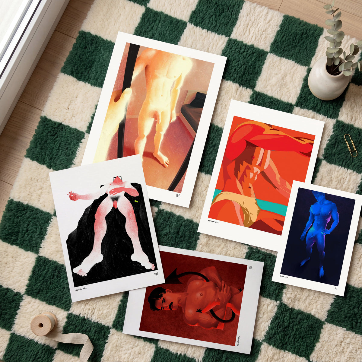 Five art prints with white borders are arranged on a green and cream checkered rug. The prints feature stylized, colorful illustrations of nude and semi-nude figures in abstract, artistic compositions.