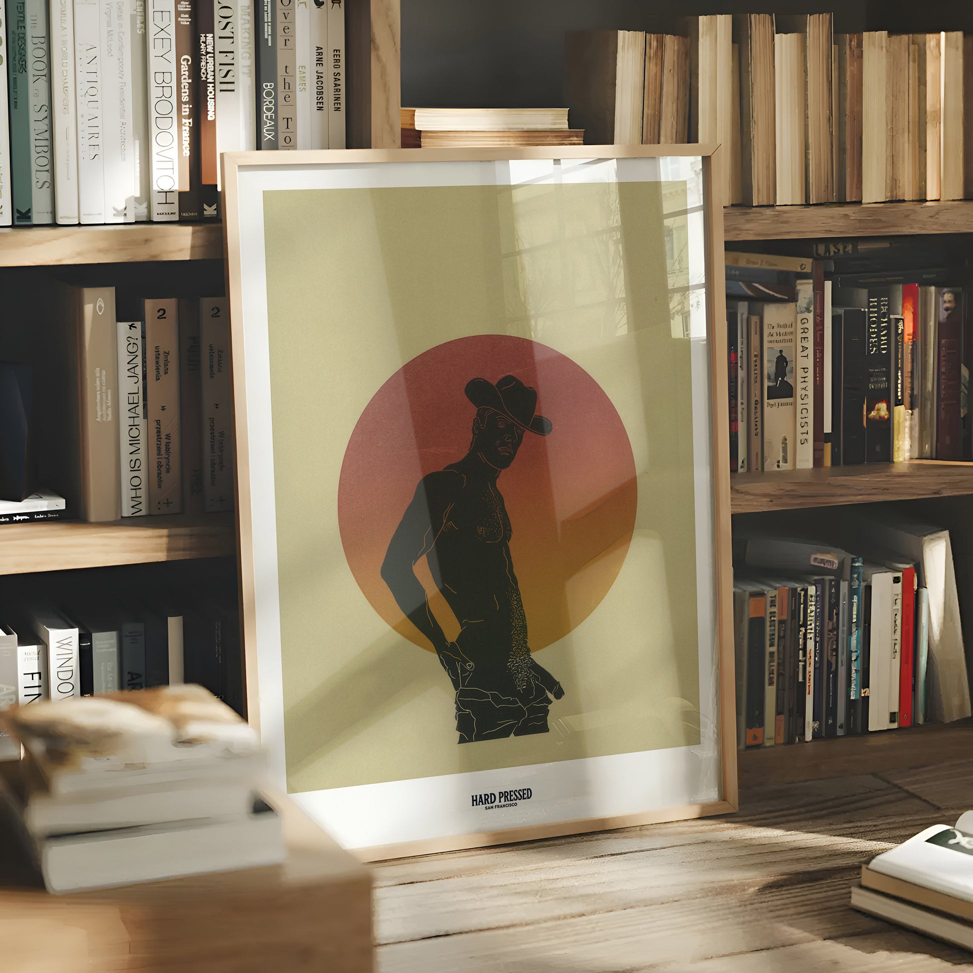 Framed artwork of a silhouette against a red circle on a bookshelf background