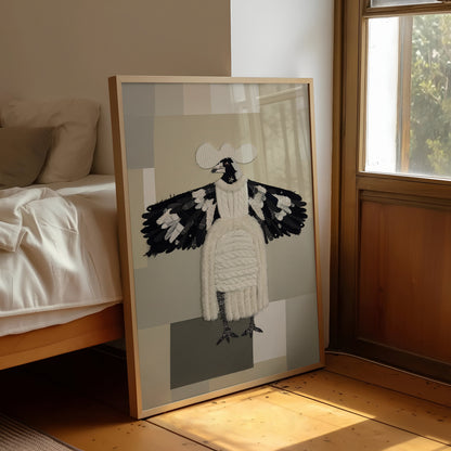 A framed art print leaning against a bed in a sunlit bedroom. The artwork shows a stylized bird figure with black and white wings and body on a muted gray and beige geometric background, enclosed in a light wood frame.