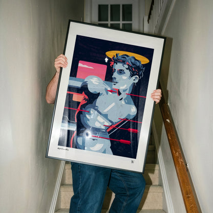 A person carrying a large framed art print up a carpeted staircase. The print features a stylized pop-art illustration of a muscular male figure with a halo, rendered in shades of blue, gray, black, and red, with a yellow halo.