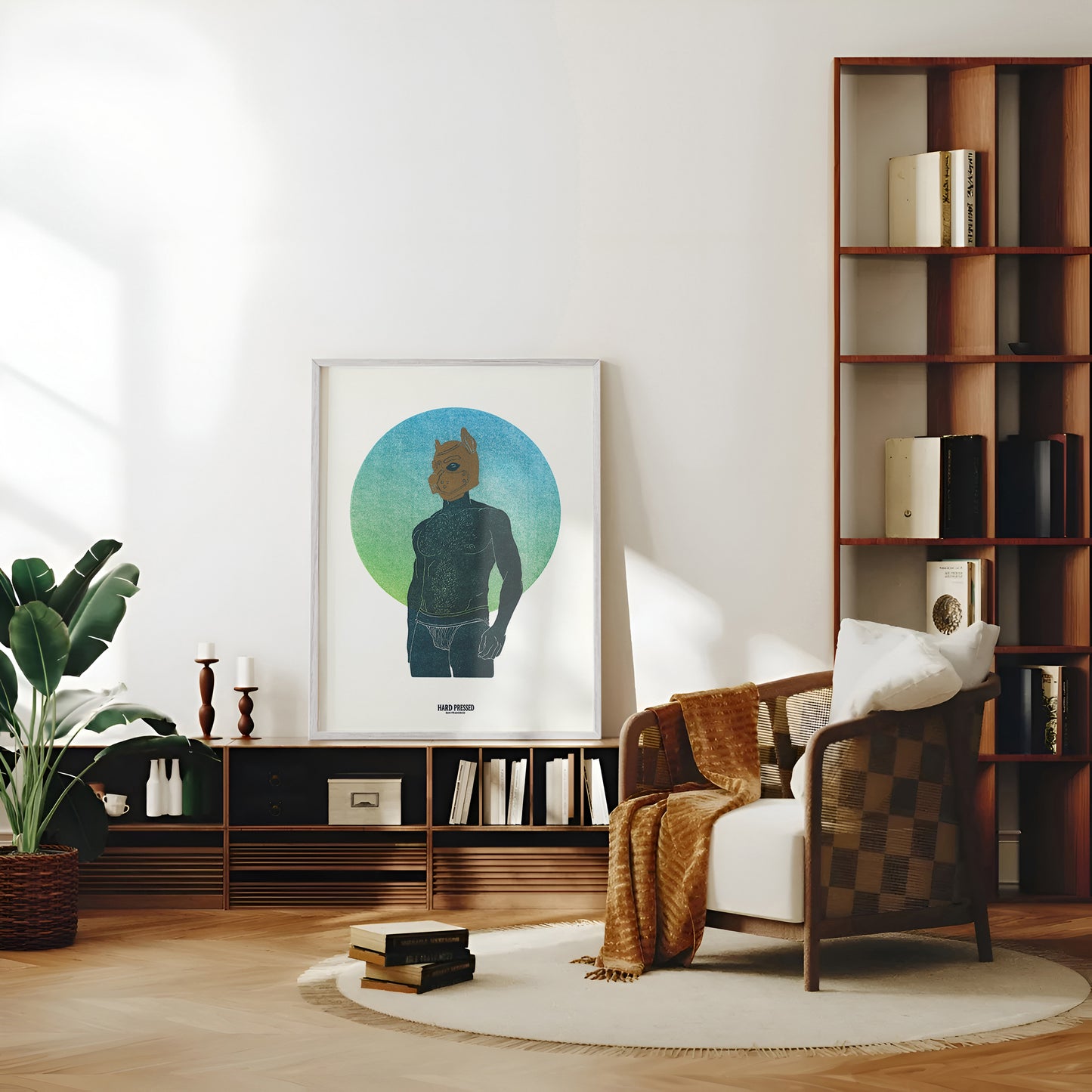 A framed art print featuring a stylized figure with a dog head mask, displayed in a modern, sunlit living room setting next to a wooden armchair and bookshelves.