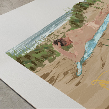 A large art print or poster displayed on a concrete floor, featuring a stylized illustration of a nude man lying on a sandy beach with green vegetation and blue water.