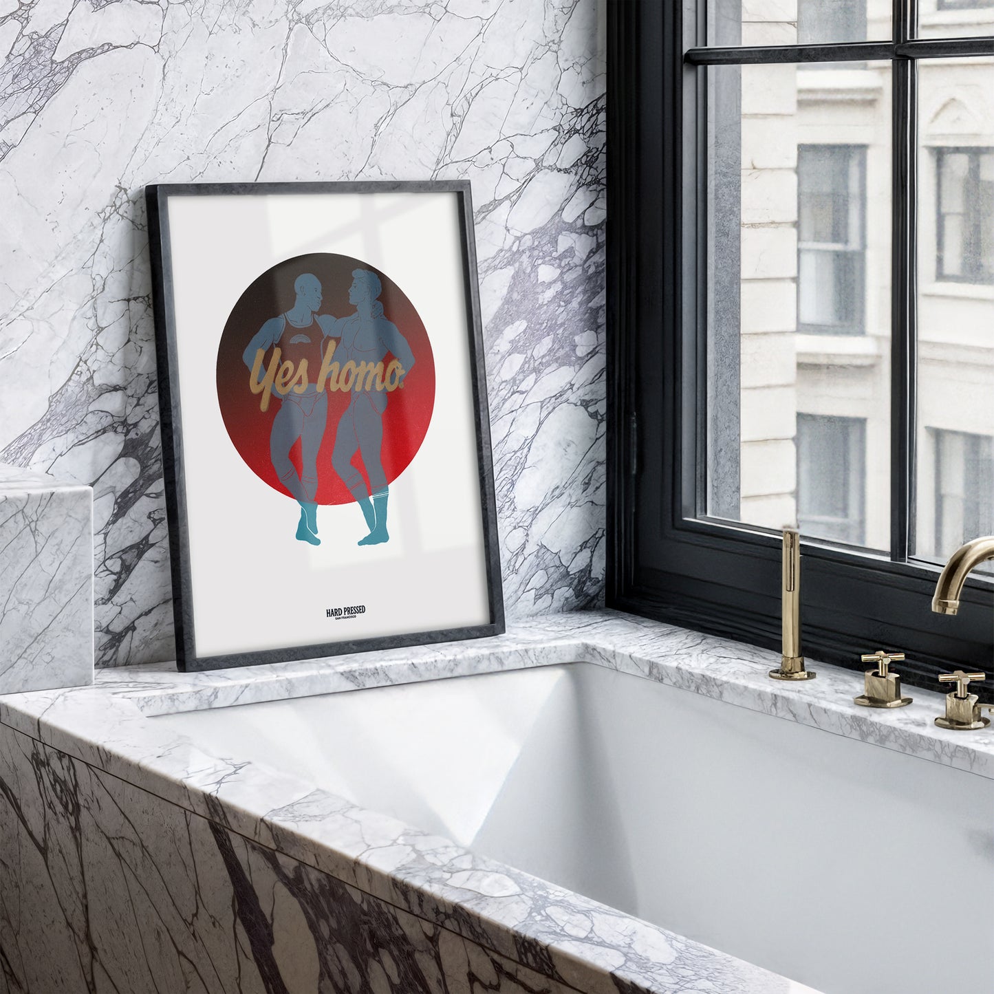A framed art print leaning against a marble wall next to a window and bathtub. The print features a circular graphic with the words 'Yes homo' in gold script over the silhouettes of two people dancing, set against a red and dark gray circle on a white background.