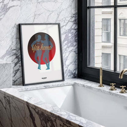 A framed art print leaning against a marble wall next to a window and bathtub. The print features a circular graphic with the words 'Yes homo' in gold script over the silhouettes of two people dancing, set against a red and dark gray circle on a white background.