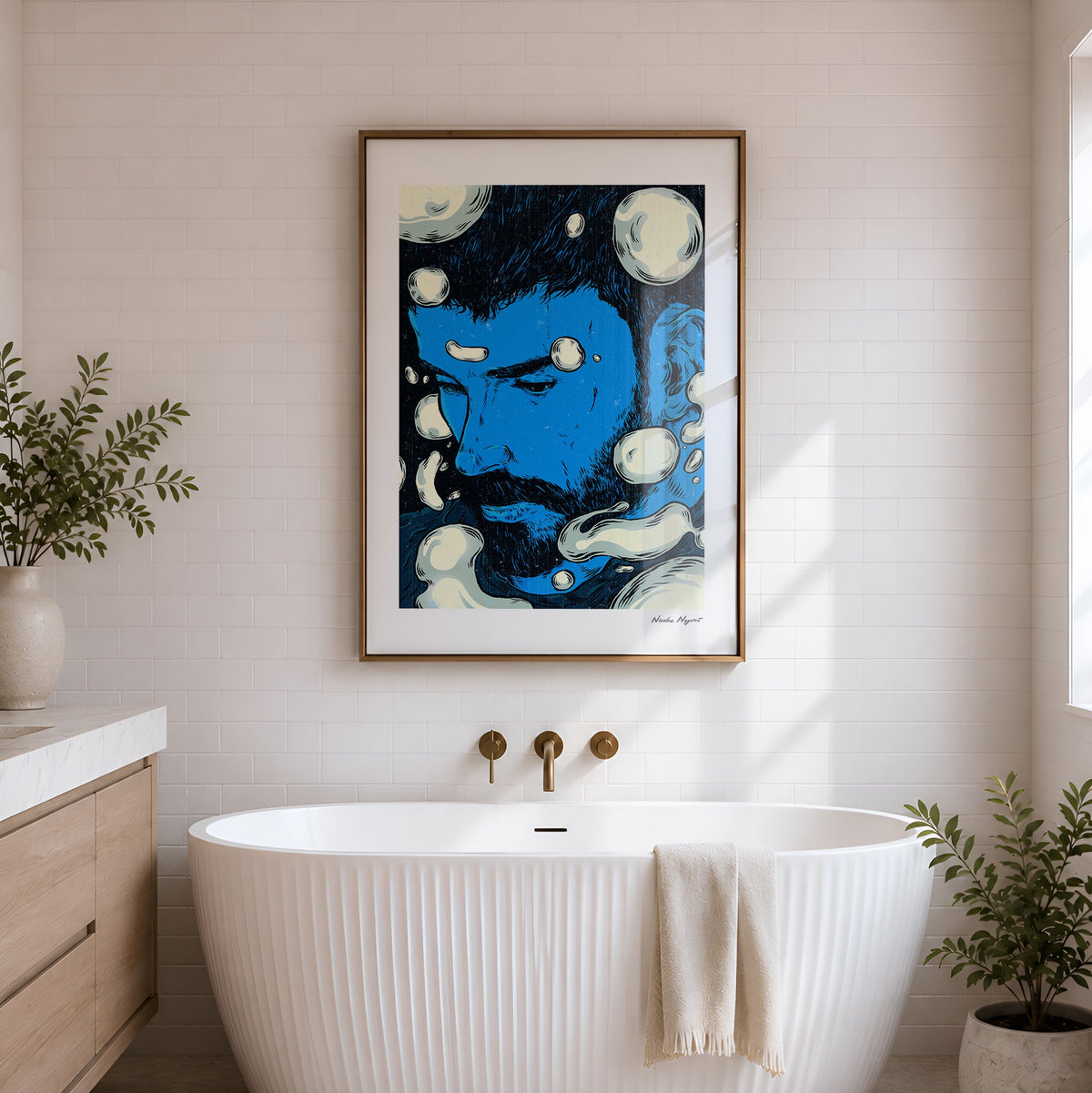 A freestanding ribbed white bathtub in a bright bathroom, with a framed abstract blue and cream artwork hanging on the wall above it. The scene includes a wood vanity on the left, potted plants, and natural light from a window.