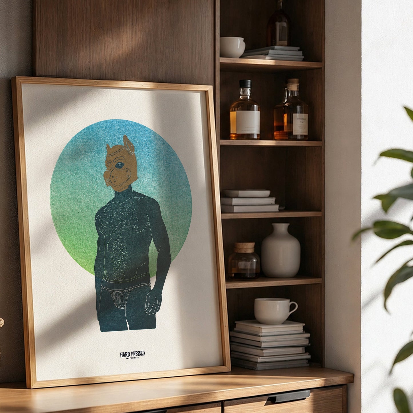 A framed art print featuring a stylized figure in front of a green and blue circular background, leaning on a wooden console table in a modern, sunlit room with shelves and decor.