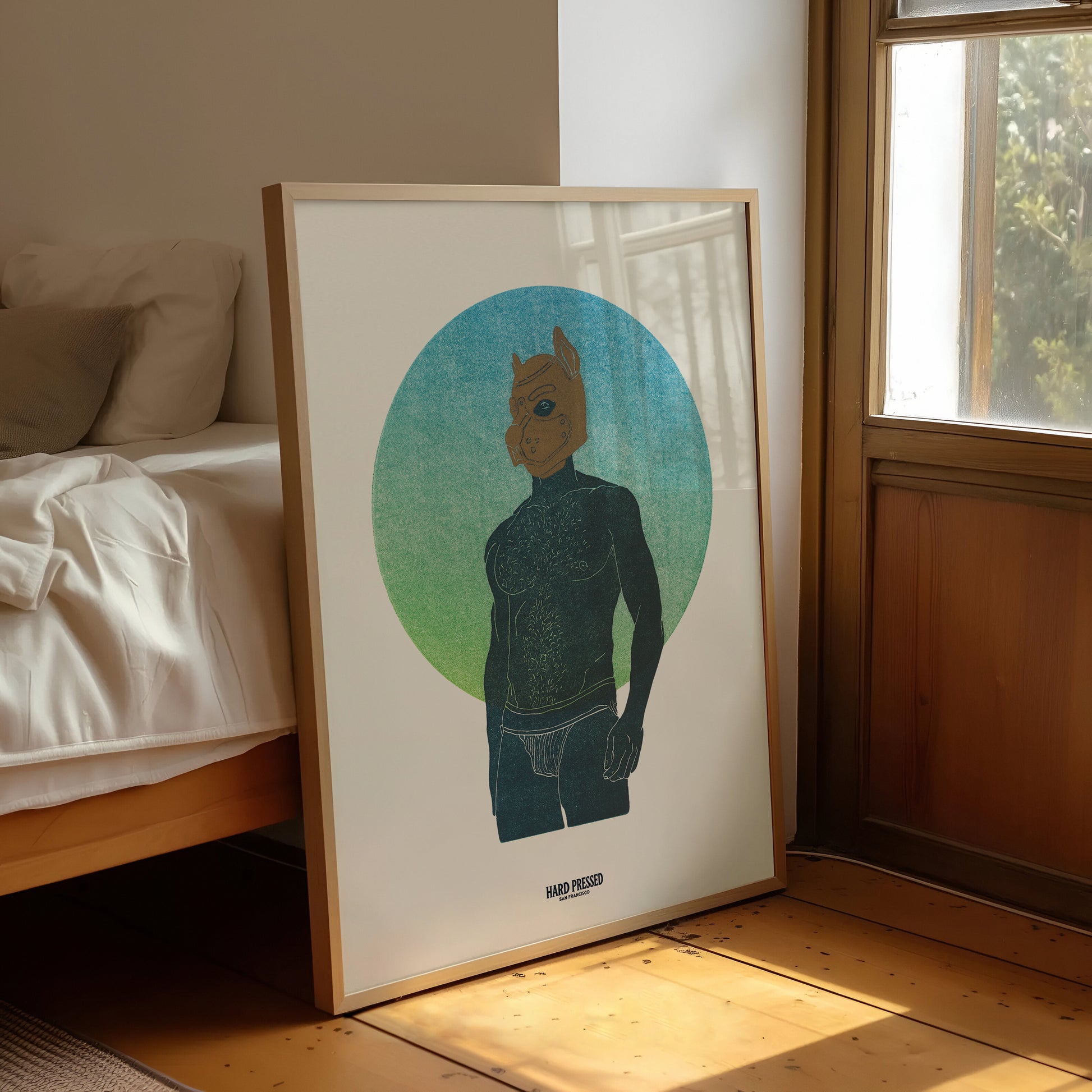 A framed art print leaning against a bed in a sunlit bedroom. The print shows a topless stylized figure standing in front of a blue-to-green circular gradient background.