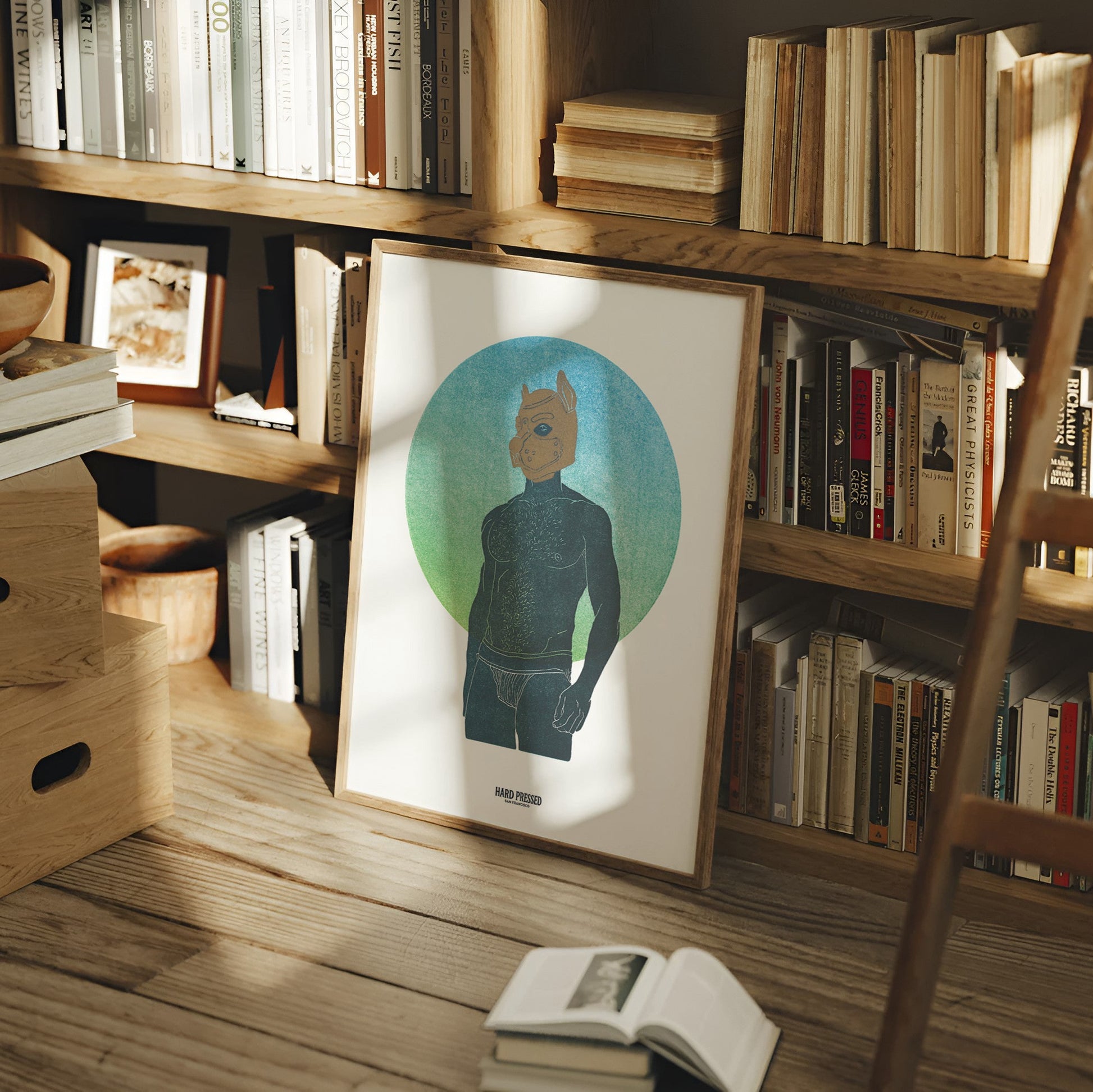 A framed art print featuring a stylized figure with a pup mask on a teal and green circular background, leaning against a wooden bookshelf in a cozy, sunlit room with books and a wooden ladder.
