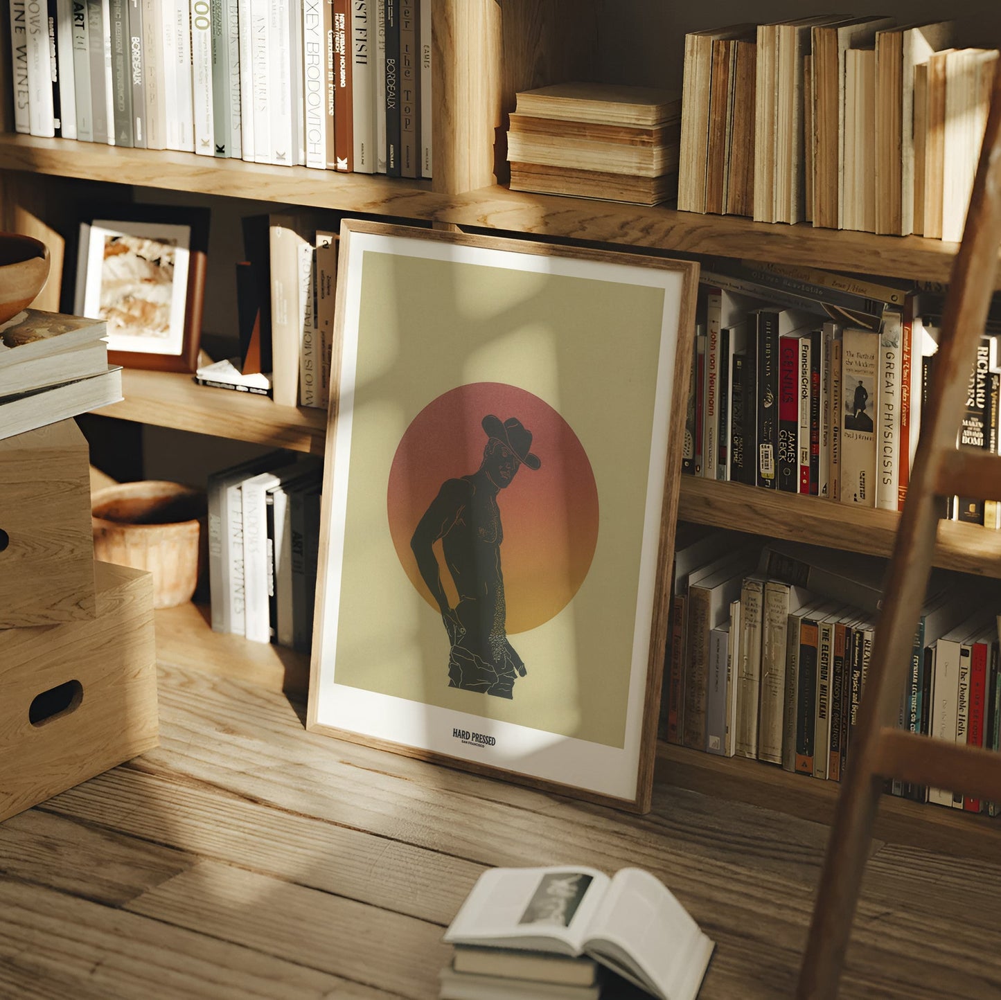 Bookshelf with books and a framed picture of a silhouette against a sunset sky.