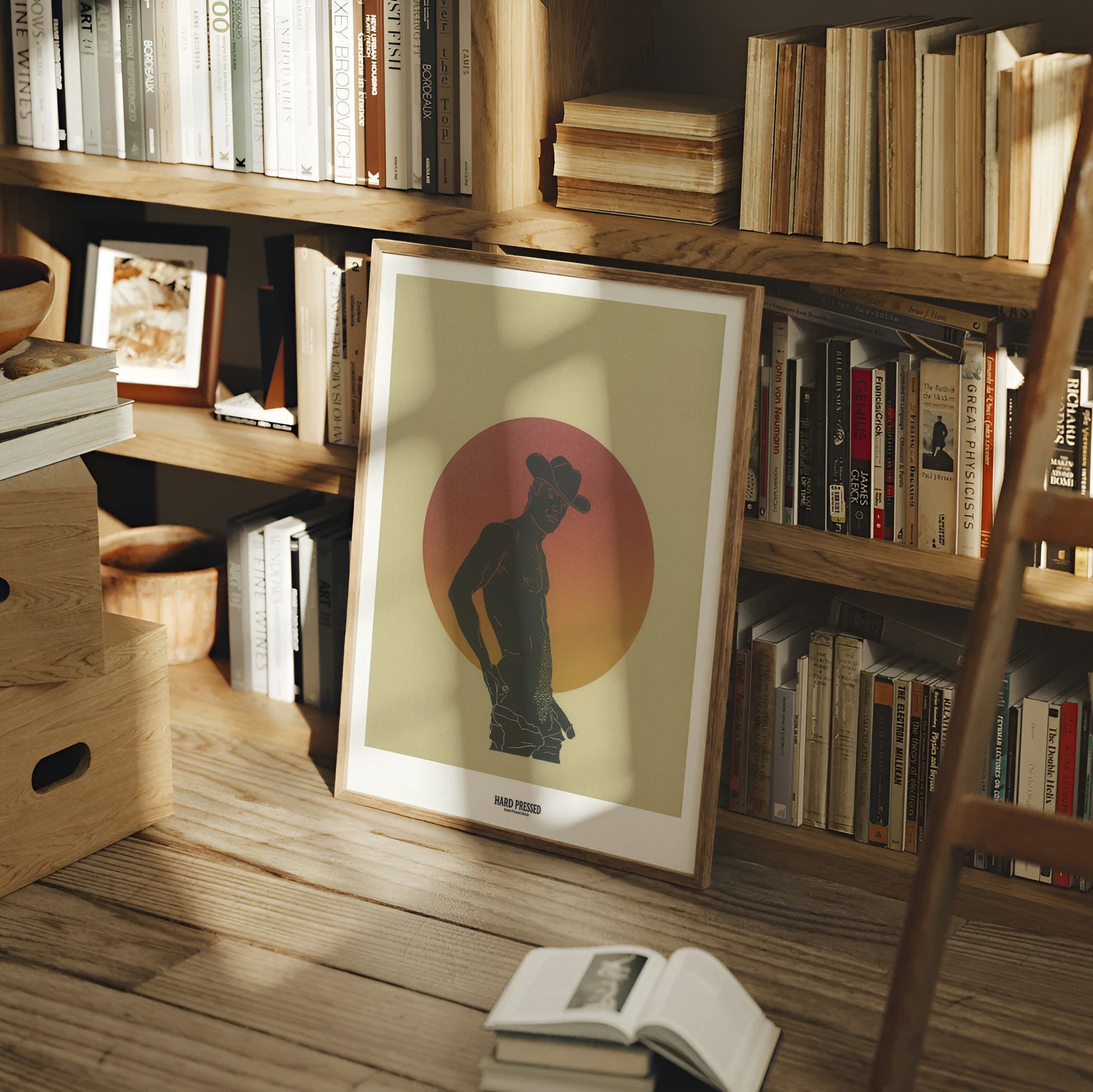 Bookshelf with books and a framed picture of a silhouette against a sunset sky.