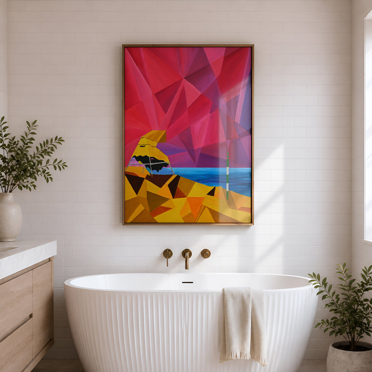 A modern freestanding bathtub in a bright bathroom, with a colorful framed abstract artwork hanging on the wall above it. The artwork features geometric shapes in pink, red, yellow, orange, and blue.