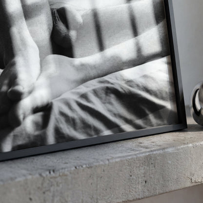 A framed black and white photograph leaning on a concrete ledge next to a polished metallic ring-shaped object.