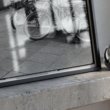 A framed black and white photograph leaning on a concrete ledge next to a shiny metallic ring-shaped object.